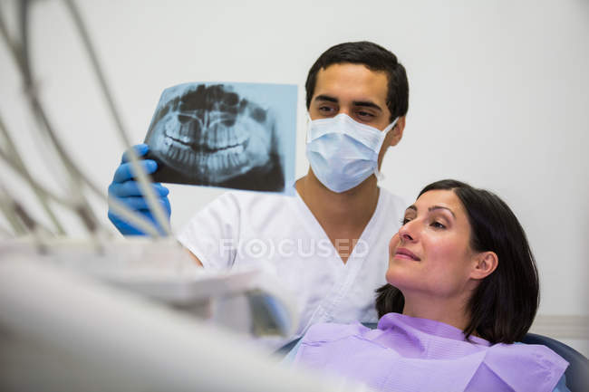 Junger männlicher Zahnarzt untersucht Röntgenbild mit Patientin in der Klinik — Stockfoto