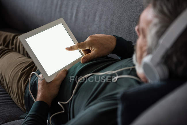 Homem ouvindo música no tablet digital em casa — Fotografia de Stock