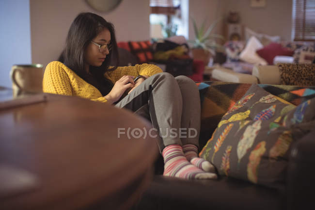 Mujer usando reloj inteligente en la sala de estar en casa - foto de stock