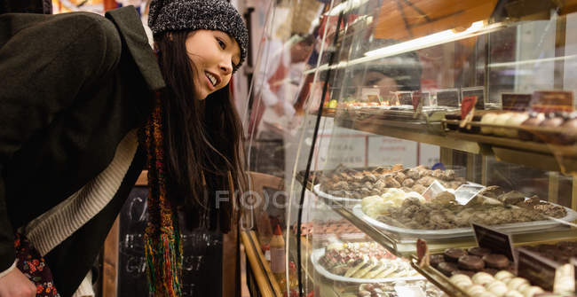 Donna che guarda i dessert al bancone dei dessert nel bancone della panetteria — Foto stock