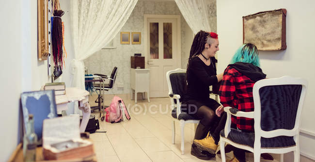 Female shop owner interacting with a customer in dreadlocks shop — Stock Photo
