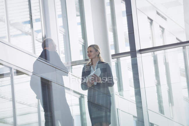 Donna d'affari che interagisce con un collega nel corridoio di un edificio per uffici — Foto stock