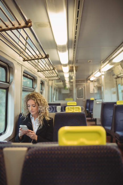 Donna d'affari di mezza età che utilizza il telefono cellulare all'interno del vano del treno — Foto stock