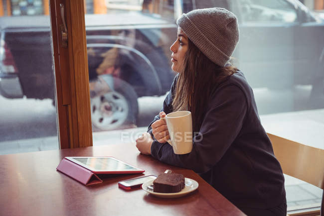 Femme en vêtements d'hiver prenant un café au restaurant — Photo de stock