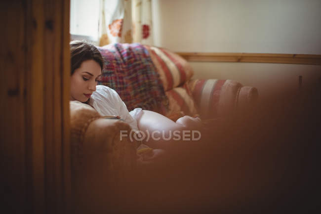 Beautiful woman lying on sofa in living room at home — Stock Photo