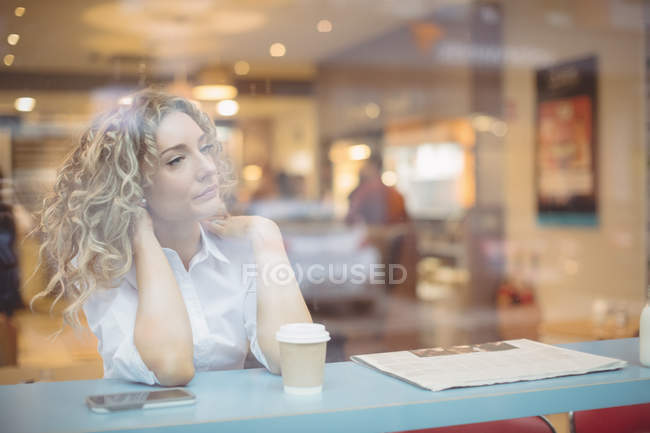 Pensativa mujer de negocios sentada en el mostrador en la cafetería - foto de stock