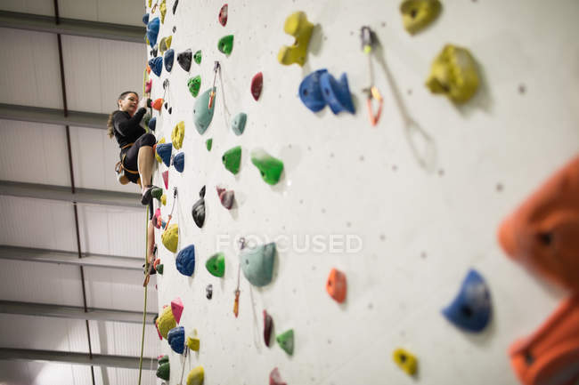 Woman practicing rock climbing on artificial climbing wall in gym — Stock Photo