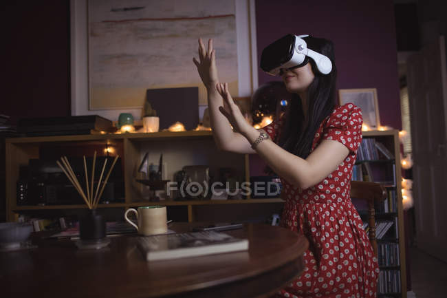 Жінка жестикулює під час використання гарнітури віртуальної реальності вдома — стокове фото