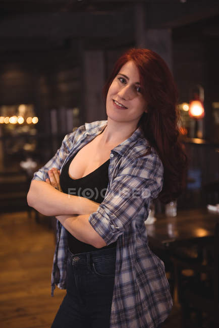 Retrato de una hermosa mujer con los brazos cruzados sonriendo en el bar - foto de stock