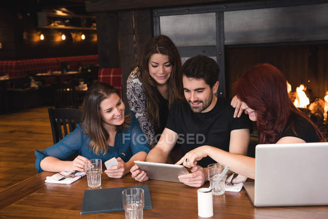 Friends sitting at table and using digital tablet in bar — Stock Photo