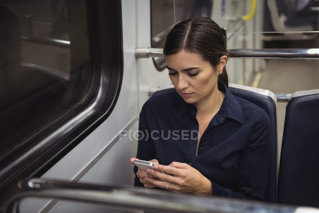 Beautiful businesswoman using phone while sitting in train — Stock Photo