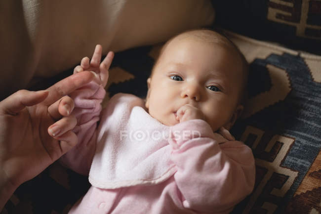 Close-up of cute baby lying on sofa in living room at home with mother hand — Stock Photo