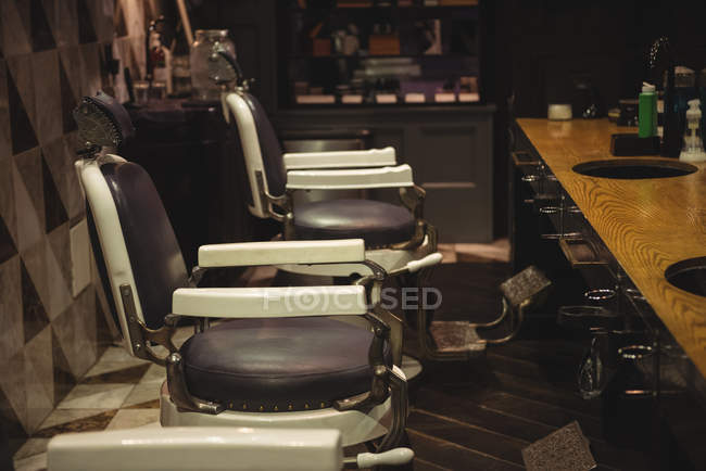 Sillas de peluquería dispuestas en fila en la peluquería - foto de stock