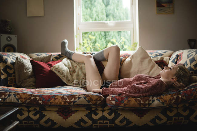 Donna sdraiata sul divano in soggiorno a casa — Foto stock