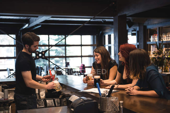 Bartender serving beer to customers at bar counter — Stock Photo