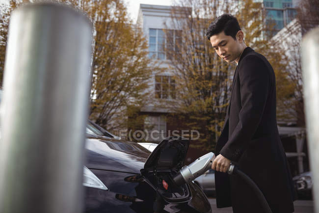 Homme confiant recharge voiture électrique à la station de recharge de véhicule électrique — Photo de stock