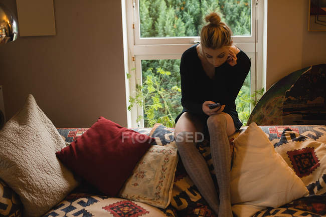 Woman lying and using mobile phone on couch in living room at home — Stock Photo