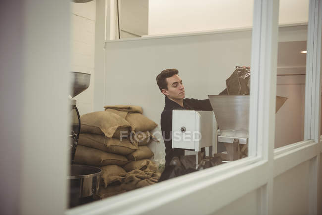 Man pouring coffee beans in coffee roasting machine in coffee shop — Stock Photo