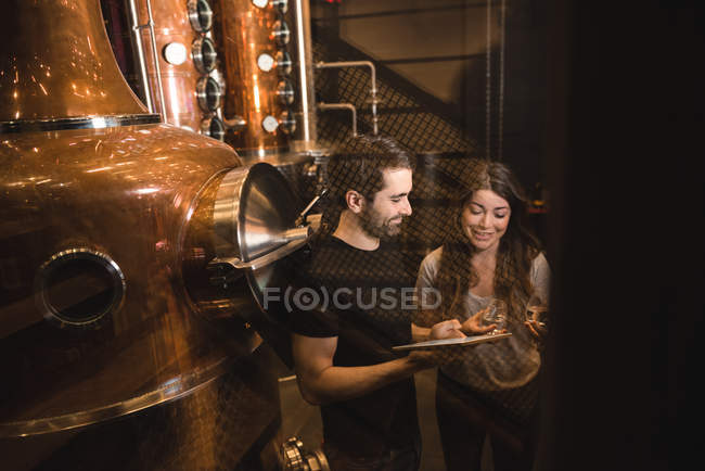 Чоловік і жінка обговорюють цифровий планшет на заводі пива — стокове фото