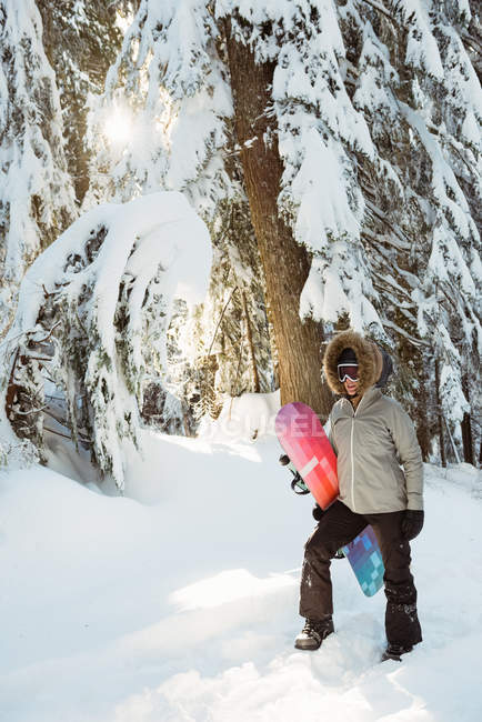 Жінка стоїть і тримає сноуборд на снігу покритій горі — стокове фото