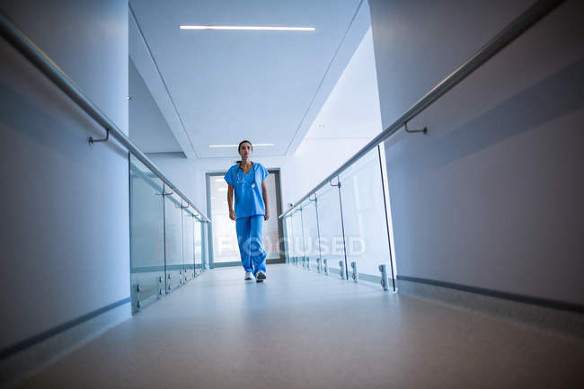 Enfermera caminando en pasillo en hospital - foto de stock
