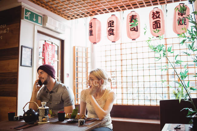 Чоловік ігнорує жінку, розмовляючи по телефону в ресторані — стокове фото