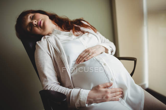 Беременная деловая женщина спит на стуле в офисе — стоковое фото