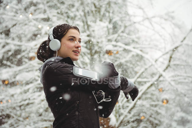 Frau hört im Winter Musik über Kopfhörer vom Smartphone — Stockfoto