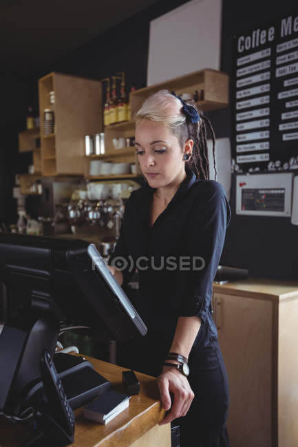 Camarera usando caja registradora en el mostrador en la cafetería - foto de stock
