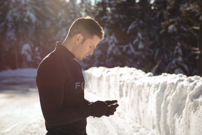 Man in warm clothing using mobile phone during winter — Stock Photo