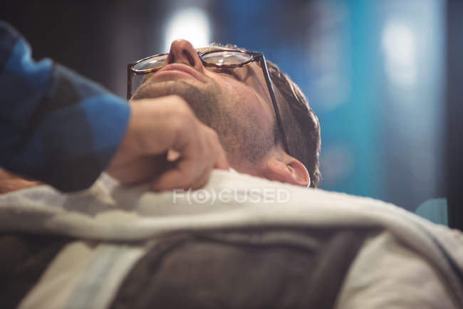 Barbeiro mão colocando toalha sobre o cliente na barbearia — Fotografia de Stock