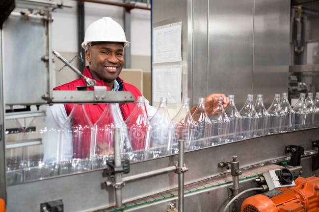 Porträt eines selbstbewussten männlichen Mitarbeiters, der Flaschen in einer Saftfabrik untersucht — Stockfoto