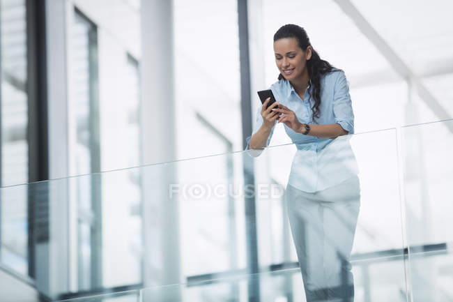 Femme d'affaires utilisant un téléphone portable à l'intérieur d'un immeuble de bureaux — Photo de stock
