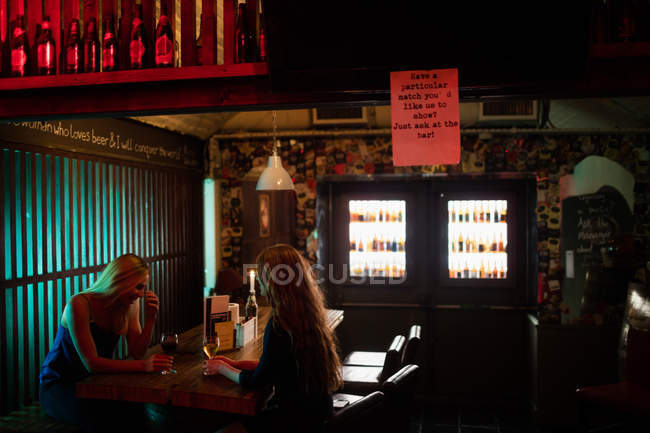 Schöne Frauen interagieren, während sie Wein in der Bar trinken — Stockfoto