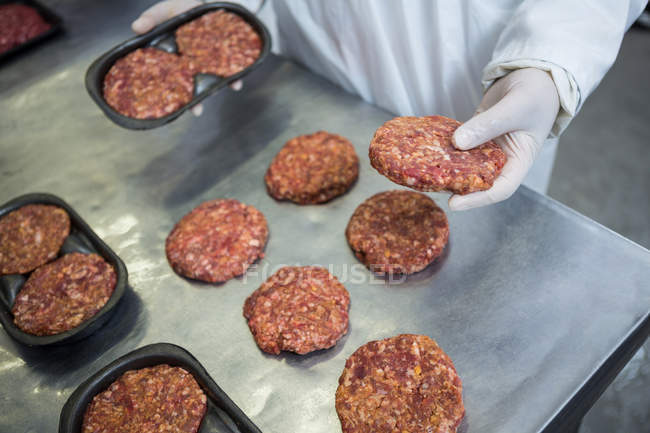 Close-up of butcher packaging patties at meat factory — Stock Photo