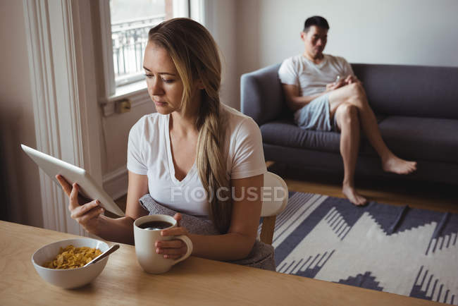 Frau nutzt digitales Tablet beim Frühstück zu Hause — Stockfoto