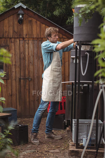 Man pouring sack of barley into wort to make beer at home brewery — Stock Photo