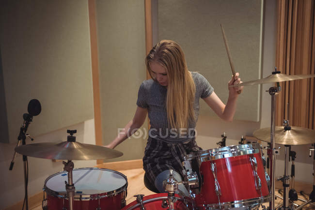 Female drummer playing a playing music on drum set in recording studio — Stock Photo