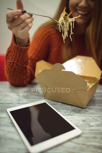 Улыбающаяся женщина ест салат в ресторане — стоковое фото