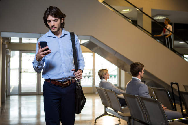 Passenger using mobile phone in waiting area at airport — Stock Photo