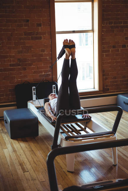Жінка практикує пілатес на реформаторі в фітнес-студії — стокове фото