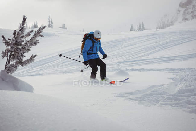 Vista lateral del esquí esquiador en las montañas cubiertas de nieve - foto de stock