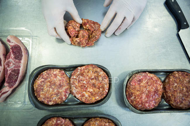 Manos de carnicero haciendo empanadas de carne en la fábrica de carne - foto de stock