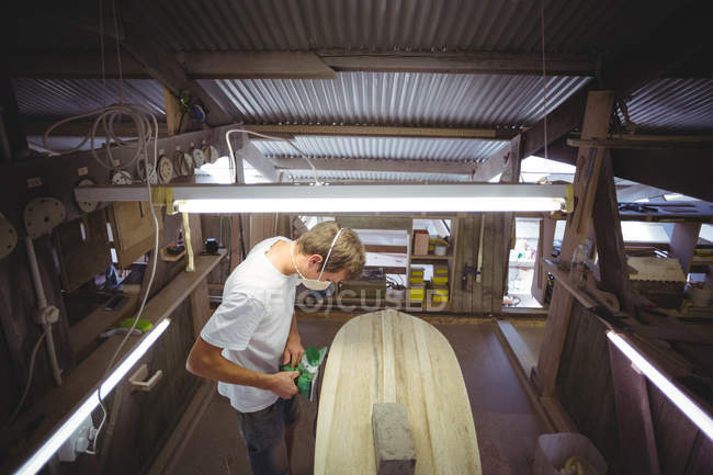 Мужчина делает доску для серфинга в интерьере мастерской — стоковое фото