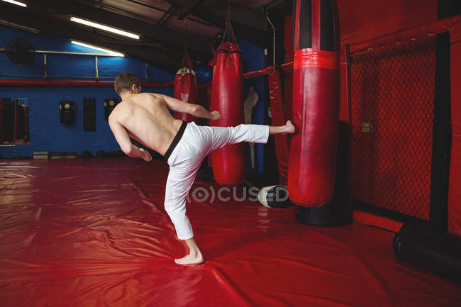 Joueur de karaté pratiquant le kickboxing dans un studio de fitness — Photo de stock
