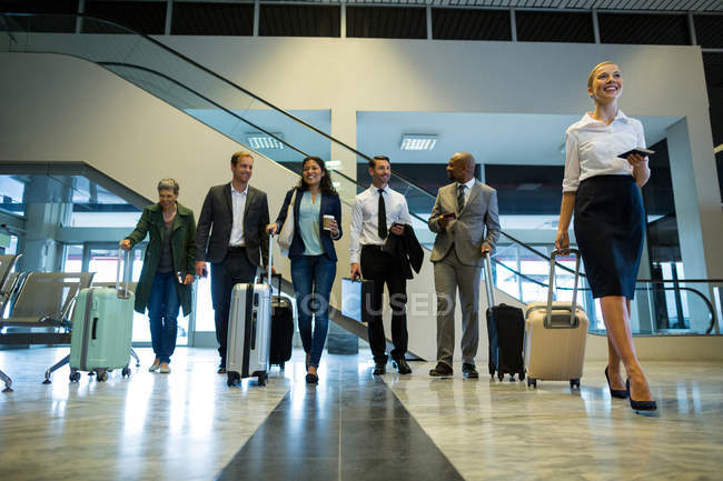 Geschäftsleute laufen mit Gepäck im Wartebereich am Flughafen — Stockfoto