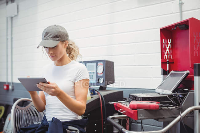 Mecânico feminino usando tablet digital na garagem de reparação — Fotografia de Stock