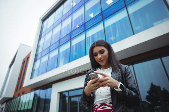 Woman using mobile phone outside the office building — Stock Photo