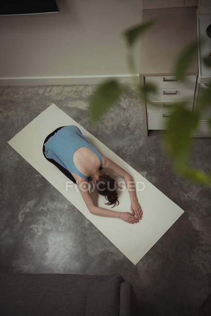 Mujer realizando yoga en cocina en casa, vista aérea - foto de stock