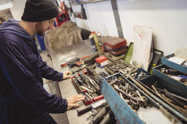 Mécanicien regardant les outils dans le garage de réparation — Photo de stock
